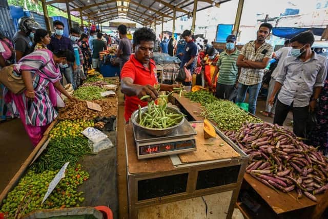 People buy vegetables at a market after authorities relaxed the ongoing curfew for a few hours in Colombo on Thursday.