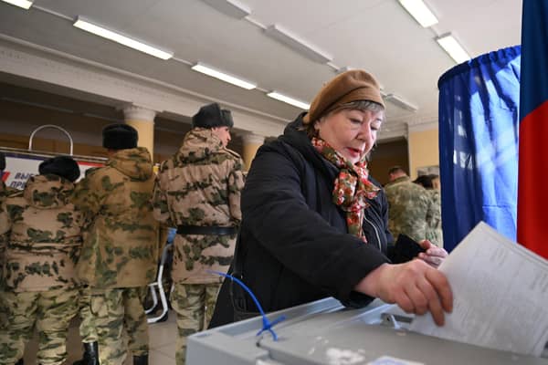 A woman casts her ballot as service members register to vote during Russia's presidential election in Moscow. (Photo by NATALIA KOLESNIKOVA / AFP)