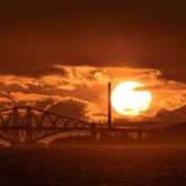 Photographer Tom Duffin, 57, captured a giant sun with clouds and the iconic bridges contrasted against it picture: SWNS