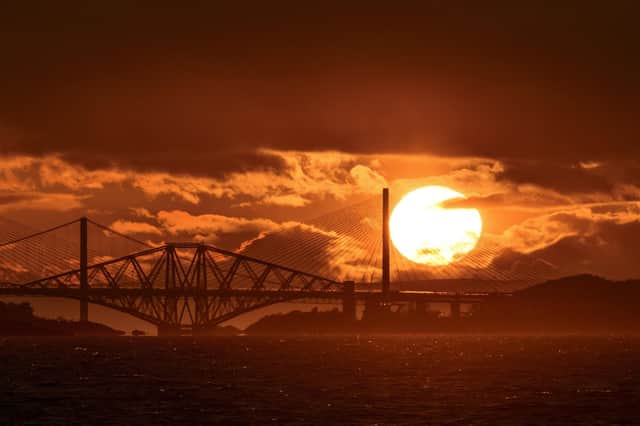 Photographer Tom Duffin, 57, captured a giant sun with clouds and the iconic bridges contrasted against it picture: SWNS
