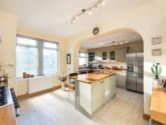 Fitted kitchen with a range of units and central island with seating, and includes a gas range cooker, double sink, boiling water tap, and separate wine fridge.
