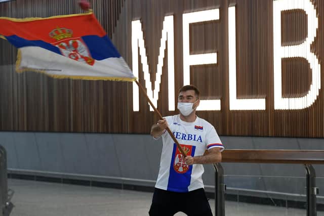 A Serbian tennis fan holds a flag as he awaits the arrival of Serbia's tennis champion Novak Djokovic at Melbourne Airport before the world number one's visa was cancelled (Photo by WILLIAM WEST/AFP via Getty Images)