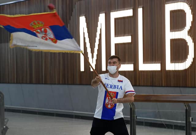 A Serbian tennis fan holds a flag as he awaits the arrival of Serbia's tennis champion Novak Djokovic at Melbourne Airport before the world number one's visa was cancelled (Photo by WILLIAM WEST/AFP via Getty Images)