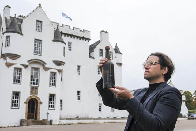 An auctioneer outside Blair Castle with one of the rare whisky bottles, thought to be 200 years old. Picture: Lisa Ferguson