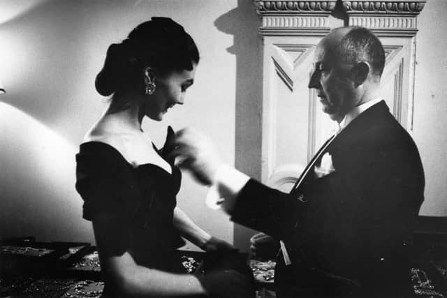 French fashion designer Christian Dior (1905 - 1957) with one of his models backstage at his 1955 fashion show at the Central Hotel, Glasgow, Scotland. The designer flew eight models, six staff and 172 dresses to Scotland for two shows, one in Glasgow and one at the Gleneagles Hotel in Perthshire, to raise money for the Friends of France, an organisation, which organises exchange visits for Scottish and French school children. Original publication: Picture Post Scottish edition - 7765 - Dior In Scotland - published, 21st May 1955. (Photo by Thurston Hopkins/Picture Post/Hulton Archive/Getty Images)