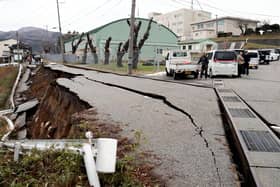People stand next to large cracks in the pavement after evacuating into a street in the city of Wajima,  (Photo by Yomiuri Shimbun/AFP via Getty Images)