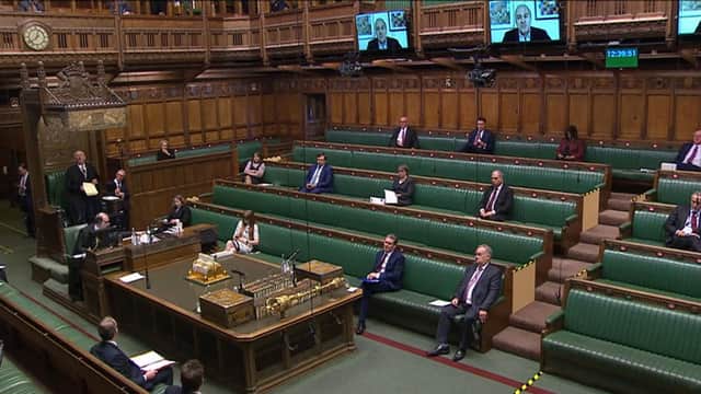 MPs are shown on screens as he speaks via videolink during Prime Minister's Questions in the House of Commons