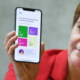 First Minister Nicola Sturgeon views the new Covid-19 track and trace app on a phone at the Scottish Parliament.