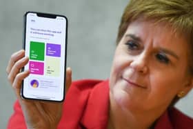 First Minister Nicola Sturgeon views the new Covid-19 track and trace app on a phone at the Scottish Parliament.