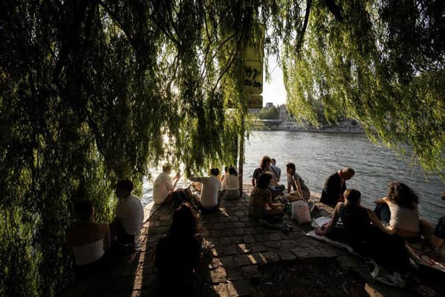 People relax by the River Seine on Ile de la Cite in Paris.