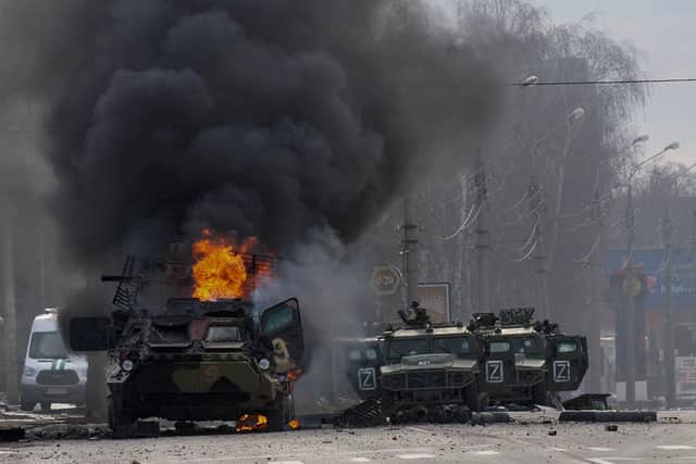 A Russian armoured personnel carrier burns and damaged light utility vehicles stand abandoned after fighting in Kharkiv, Ukraine