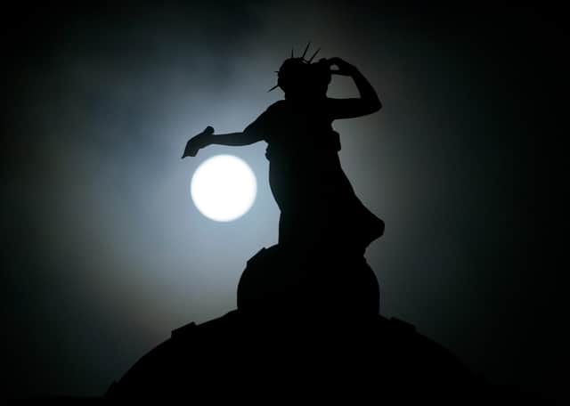 Seen above: the full moon behind Thomas Clapperton's bronze statue called Literature which sits on top of the Mitchell Library, Glasgow, Scotland.