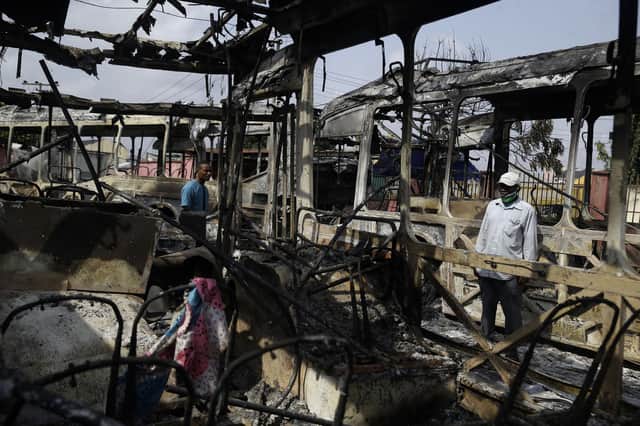 People look at burnout buses in Lagos. Nigeria's president says 51 civilians were killed in unrest following days of peaceful protests over police abuses. Picture: AP Photo/Sunday Alamba