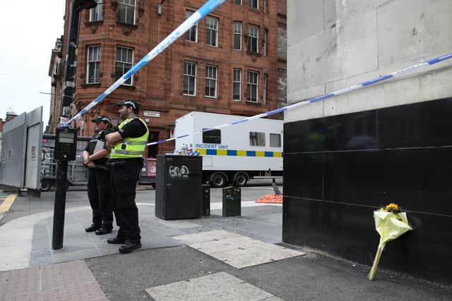 Police, alongside a floral tribute, at the scene in West George Street, Glasgow