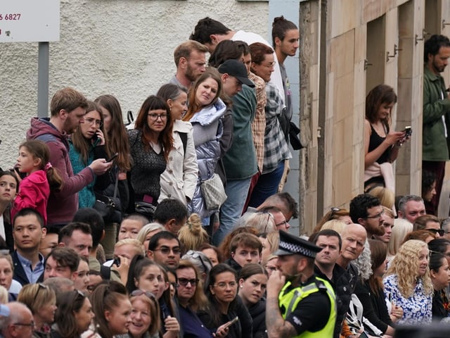 People in Cannongate, Edinburgh ahead of the passing of Queen Elizabeth II's coffin on its journey from Balmoral to Edinburgh, where it will lie at rest at the Palace of Holyroodhouse. Picture date: Sunday September 11, 2022.