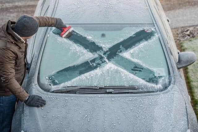 A man carving the Scottish flag into the frost on his windscreen picture: Phil Wilkinson