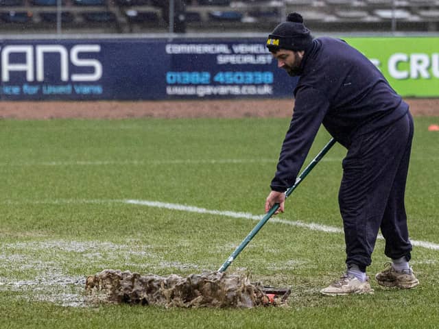 A Dundee groundsman sweeps water off the pitch at Dens Park prior to the match against Aberdeen being postponed. (Photo by Mark Scates / SNS Group)