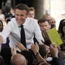 Centrist candidate and French President Emmanuel Macron shakes hands to residents during a campaign rally on Friday