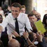 Centrist candidate and French President Emmanuel Macron shakes hands to residents during a campaign rally on Friday