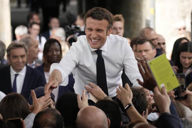 Centrist candidate and French President Emmanuel Macron shakes hands to residents during a campaign rally on Friday