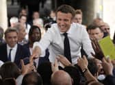 Centrist candidate and French President Emmanuel Macron shakes hands to residents during a campaign rally on Friday