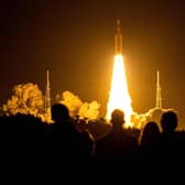 Spectators watch as the Artemis I unmanned lunar rocket lifts off from launch pad