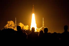 Spectators watch as the Artemis I unmanned lunar rocket lifts off from launch pad