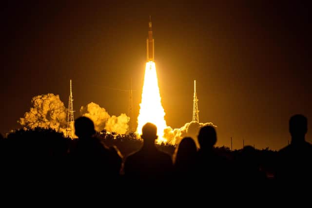 Spectators watch as the Artemis I unmanned lunar rocket lifts off from launch pad