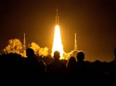 Spectators watch as the Artemis I unmanned lunar rocket lifts off from launch pad