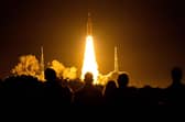 Spectators watch as the Artemis I unmanned lunar rocket lifts off from launch pad