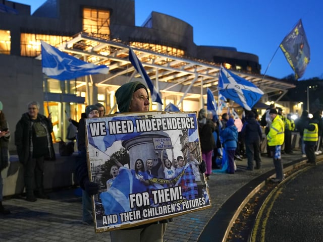 A sign reads "We need independence" outside the Scottish Parliament