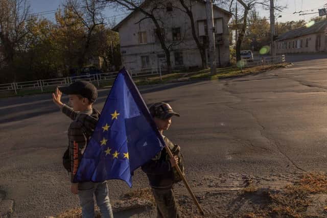 Children with an European flag wave to cars driving past in the southern Ukrainian city of Kherson.