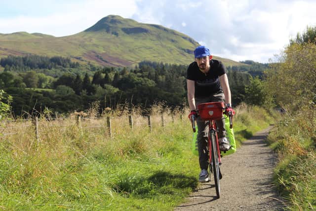 Sam Johnson cycling along the John Muir Way in front of Dumgoyne Hill, Loch Lomond and The Trossachs National Park
