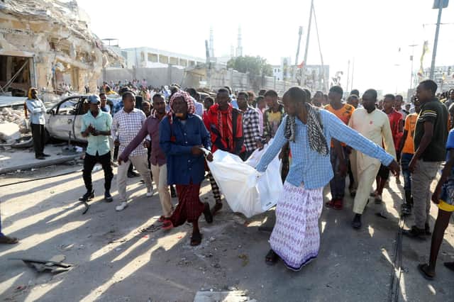 Residents carry the body of a victim in Mogadishu on October 30, 2022 after an car bombing targeted the education ministry on October 29, 2022. - Two huge car bombings rocked Somalia's education ministry in the capital Mogadishu causing casualties and shattering windows of nearby buildings, police and witnesses said. The "simultaneous explosions occurred along the Zobe road and there are various casualties. (Photo by HASSAN ALI ELMI / AFP) (Photo by HASSAN ALI ELMI/AFP via Getty Images)