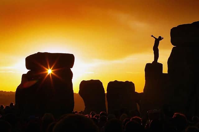 A reveller greets the sun as it rises above Stonehenge on the day of the Summer Solstice. Photo by Scott Barbour/Getty Images
