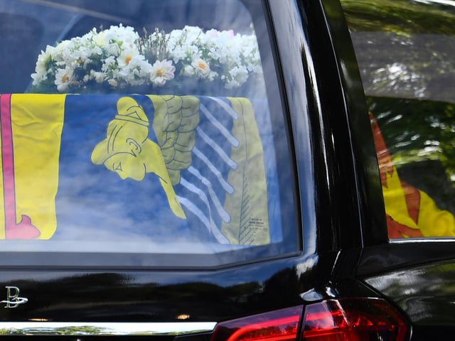 The hearse carrying the coffin of Queen Elizabeth II covered with the Royal Standard of Scotland and flowers is driven away from Balmoral Castle (Photo by ANDY BUCHANAN/AFP via Getty Images)