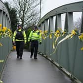 Police officers walk past yellow ribbons and messages of hope tied to a bridge for Nicola Bulley over the River Wyre in St Michael's on Wyre, Lancashire, as police continue their search for Ms Bulley, 45, who vanished on January 27 while walking her springer spaniel Willow shortly after dropping her daughters, aged six and nine, at school.