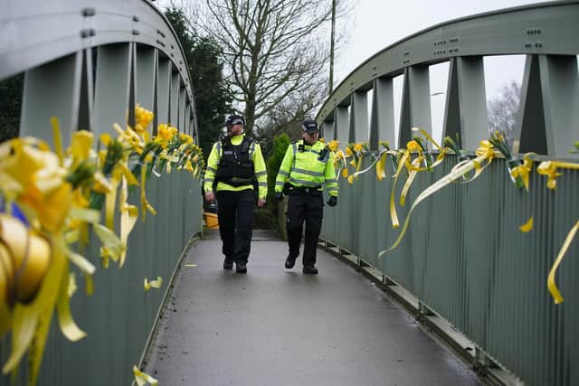 Police officers walk past yellow ribbons and messages of hope tied to a bridge for Nicola Bulley over the River Wyre in St Michael's on Wyre, Lancashire, as police continue their search for Ms Bulley, 45, who vanished on January 27 while walking her springer spaniel Willow shortly after dropping her daughters, aged six and nine, at school.