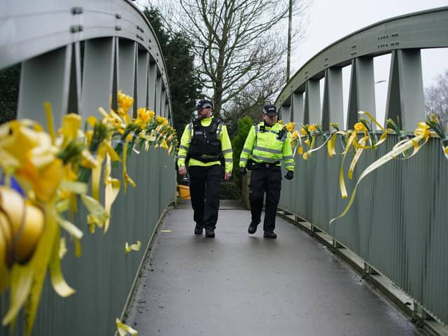 Police officers walk past yellow ribbons and messages of hope tied to a bridge for Nicola Bulley over the River Wyre in St Michael's on Wyre, Lancashire, as police continue their search for Ms Bulley, 45, who vanished on January 27 while walking her springer spaniel Willow shortly after dropping her daughters, aged six and nine, at school.