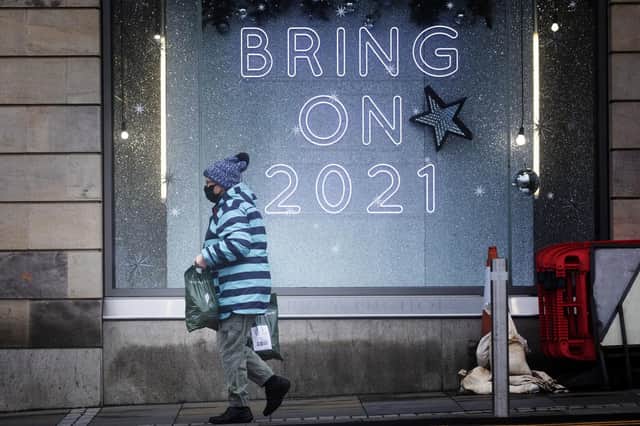 A shopper wearing a protective face mask walks past a shop sign which carries a message all of us would agree with