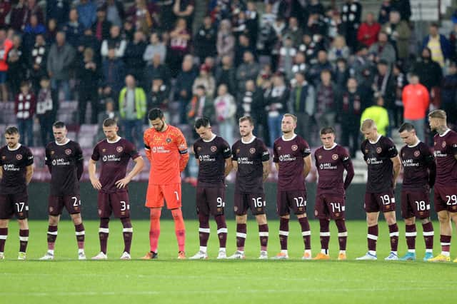 Hearts players stand wearing black armbands before the second half following the announcement of the death of Queen Elizabeth II.