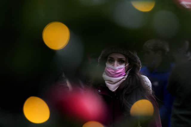 A woman wears a face covering as she walks past a Christmas Lights decoration in London. Picture: AP Photo/Frank Augstein