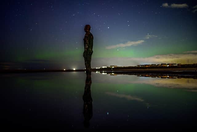 The aurora borealis, also known as the northern lights, are seen over one of the iron men statues at Anthony Gormley's Another Place, on Crosby Beach, Merseyside. Picture: Peter Byrne/PA Wire