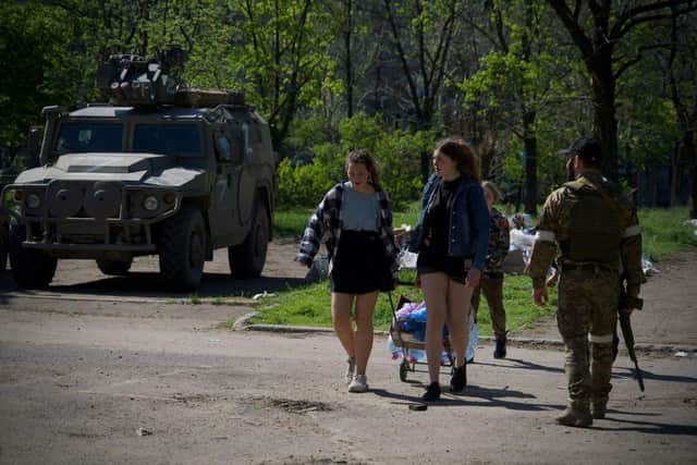 Residents walk in the city of Mariupol as the self-proclaimed Donetsk People's Republic (DNR) servicemen guard an area earlier this week, amid the ongoing Russian military action in Ukraine. Picture: AFP via Getty Images