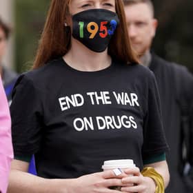 A woman wearing a face mask showing 1935, the number of drug overdose deaths in Scotland, in 2021.