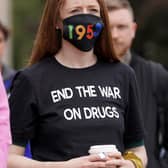 A woman wearing a face mask showing 1935, the number of drug overdose deaths in Scotland, in 2021.