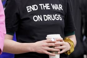 A woman wearing a face mask showing 1935, the number of drug overdose deaths in Scotland, in 2021.