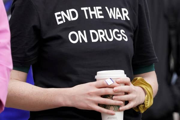 A woman wearing a face mask showing 1935, the number of drug overdose deaths in Scotland, in 2021.