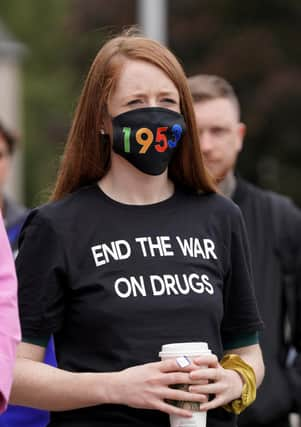 A woman wearing a face mask showing 1935, the number of drug overdose deaths in Scotland, in 2021.