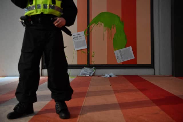 A police officer stands near pamphlets and green paint which were thrown by climate activists at the exterior of the headquarters of energy company Scottish Power in Glasgow on November 11, 2021, during the COP26 UN Climate Change Conference. (Photo by BEN STANSALL/AFP via Getty Images)